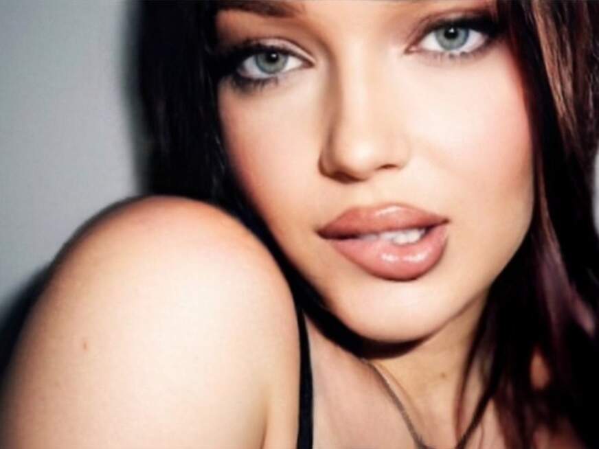 Olivia mit brünettem Haar und blauen Augen in natürlicher Pose