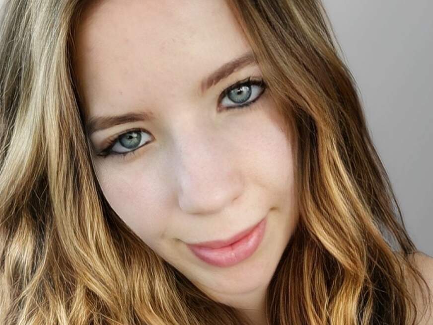Lola mit dunkelblondem Haar und blauen Augen in natürlicher Pose